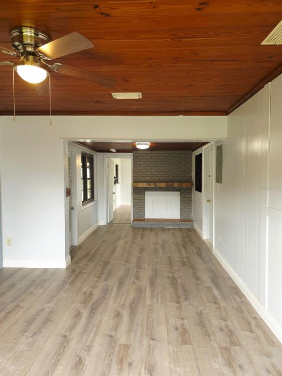 A living room features wood-paneled ceilings, light-colored flooring, and a gray brick fireplace — 1818 MINNESOTA AVENUE UNIT B, ST CLOUD, FL