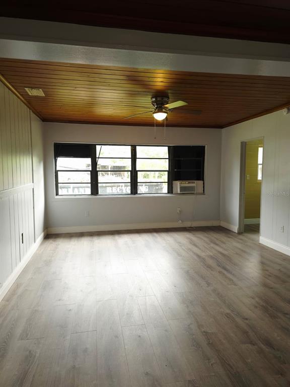 A living room features wood-paneled ceilings, light gray walls, and wood-look flooring — 1818 MINNESOTA AVENUE UNIT B, ST CLOUD, FL