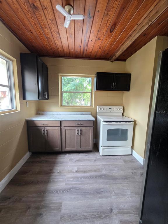 A kitchen with wood-paneled ceiling, dark cabinets, white countertops, and a white stove — 1818 MINNESOTA AVENUE UNIT B, ST CLOUD, FL