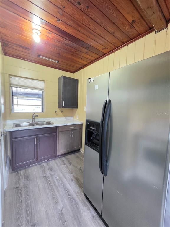 A kitchen features dark wood cabinets, a stainless steel refrigerator, and a wood-paneled ceiling — 1818 MINNESOTA AVENUE UNIT B, ST CLOUD, FL