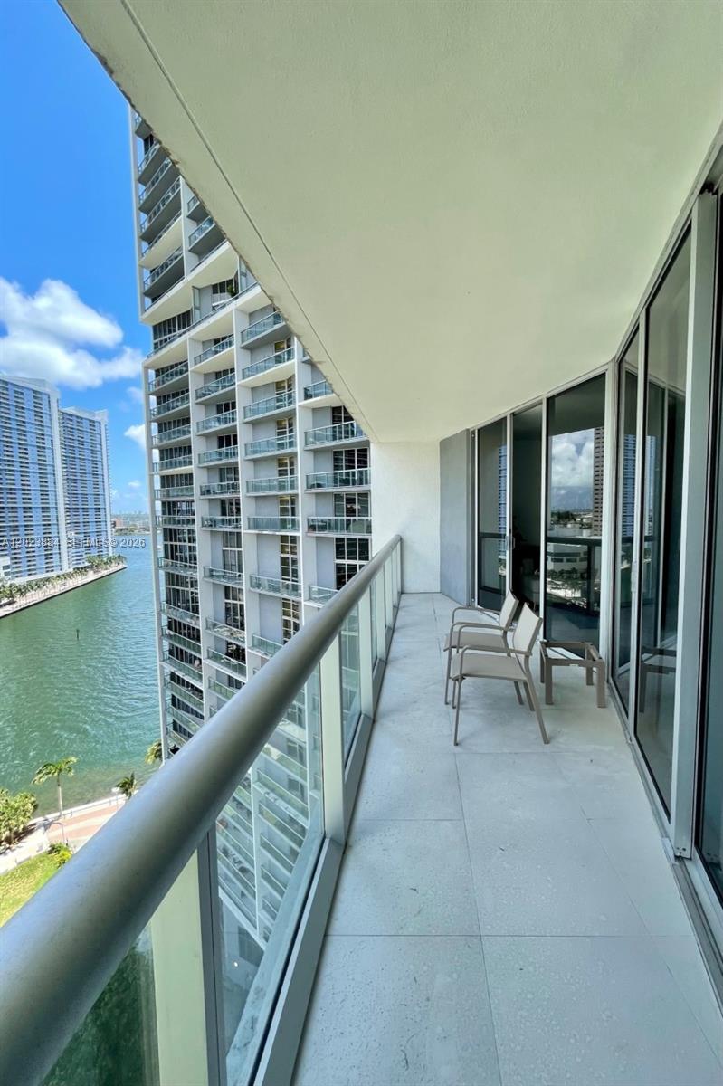 A balcony with glass railings overlooks a waterway and neighboring high-rise apartment buildings — 475 Brickell Avenue # 1614, Miami FL 33131, MIAMI, FL