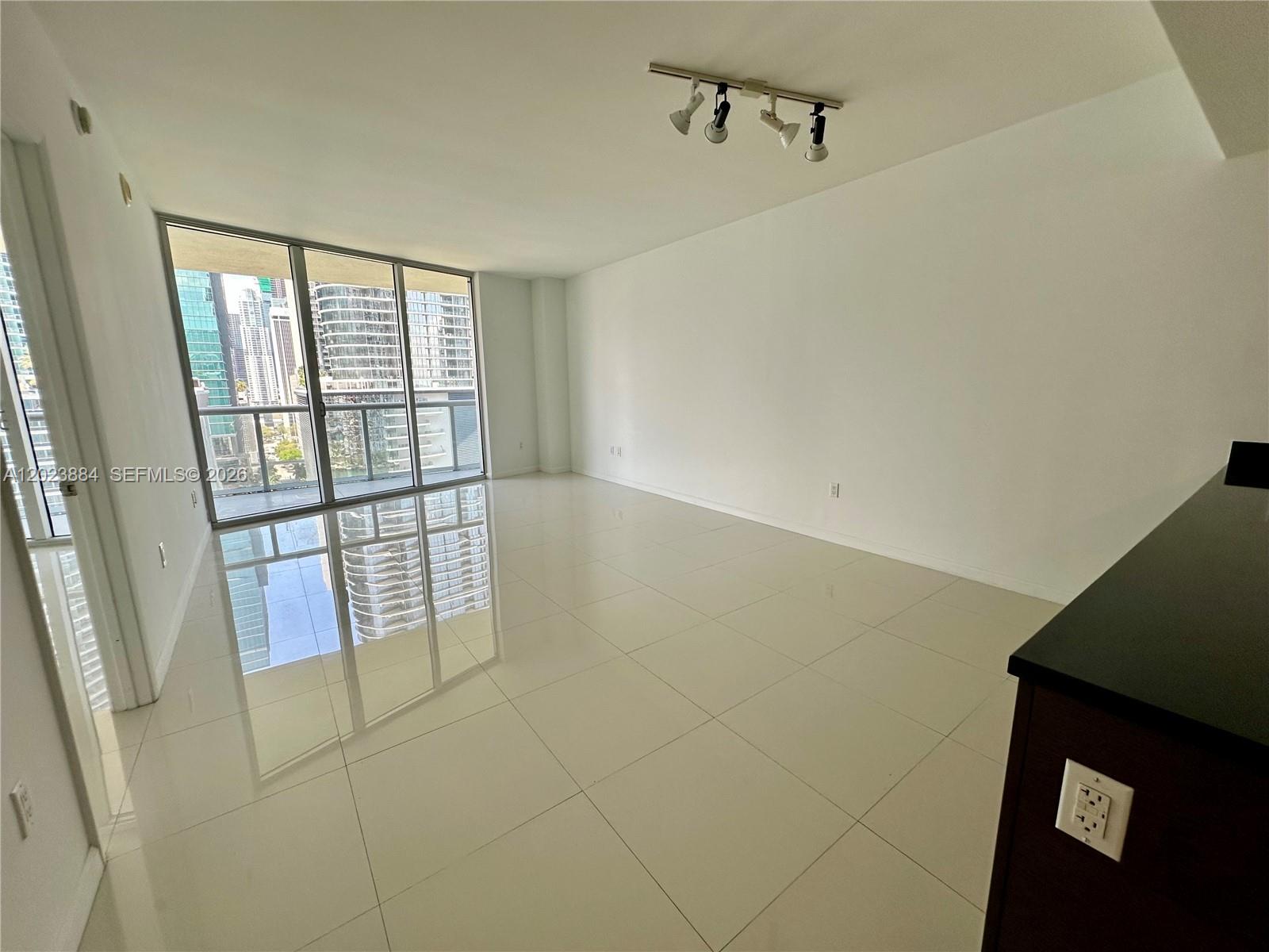 An empty room with white tile floors, a track light, and floor-to-ceiling windows — 475 Brickell Avenue # 1614, Miami FL 33131, MIAMI, FL