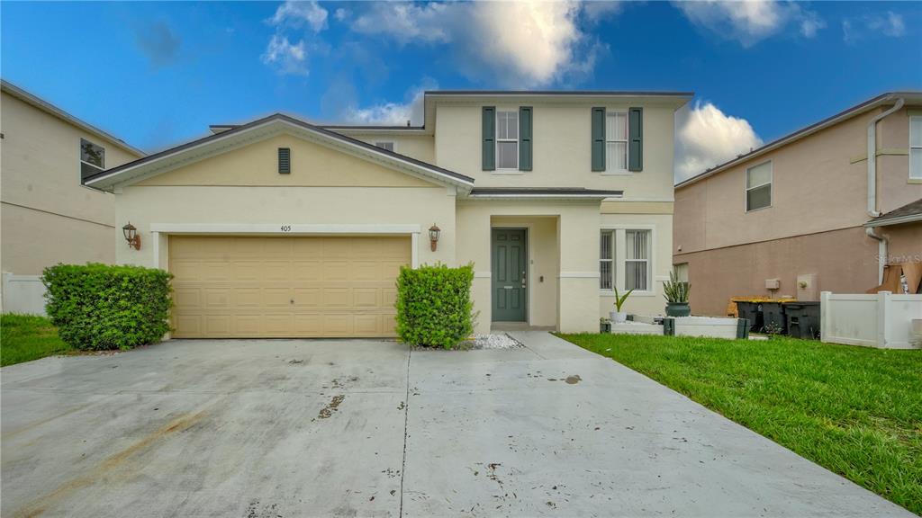 A two-story house with a beige stucco exterior, a two-car garage, and a concrete driveway — 405 KETTERING ROAD, DAVENPORT, FL