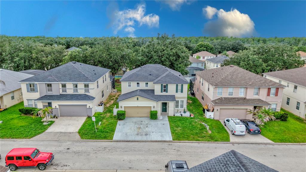 An aerial view shows three suburban houses with driveways and lawns along a paved street — 405 KETTERING ROAD, DAVENPORT, FL