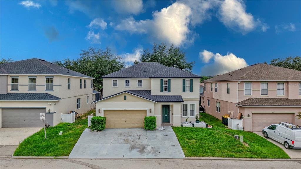 A two-story suburban house with a tan stucco exterior, a two-car garage, and a driveway — 405 KETTERING ROAD, DAVENPORT, FL