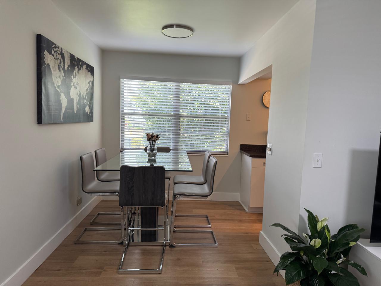 A dining room with a glass table, four chairs, a world map, and wood flooring — 124 Oakridge I # 124, Deerfield Beach FL 33442, DEERFIELD BEACH, FL