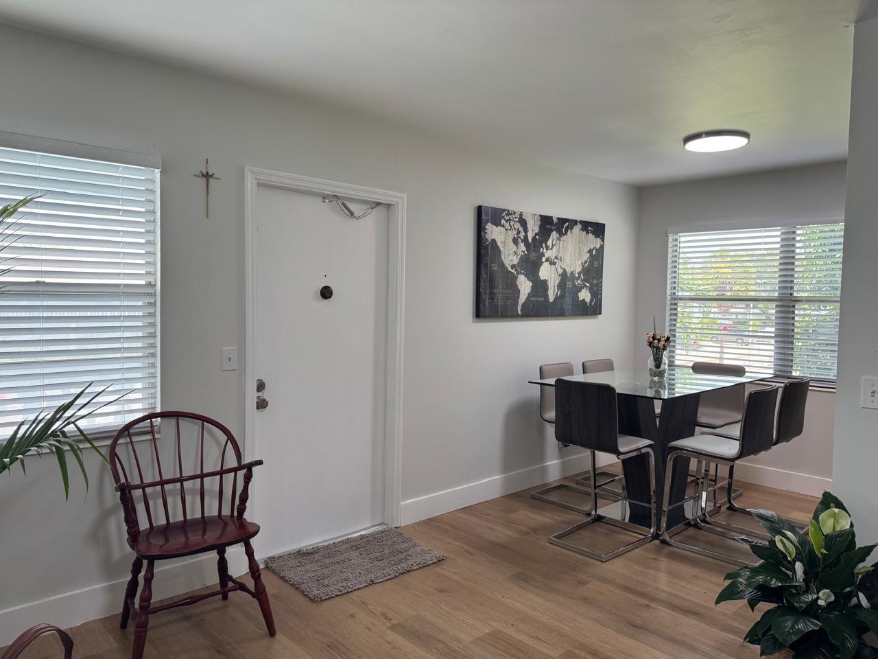 A dining area with a glass table, modern chairs, a world map, and a front door — 124 Oakridge I # 124, Deerfield Beach FL 33442, DEERFIELD BEACH, FL