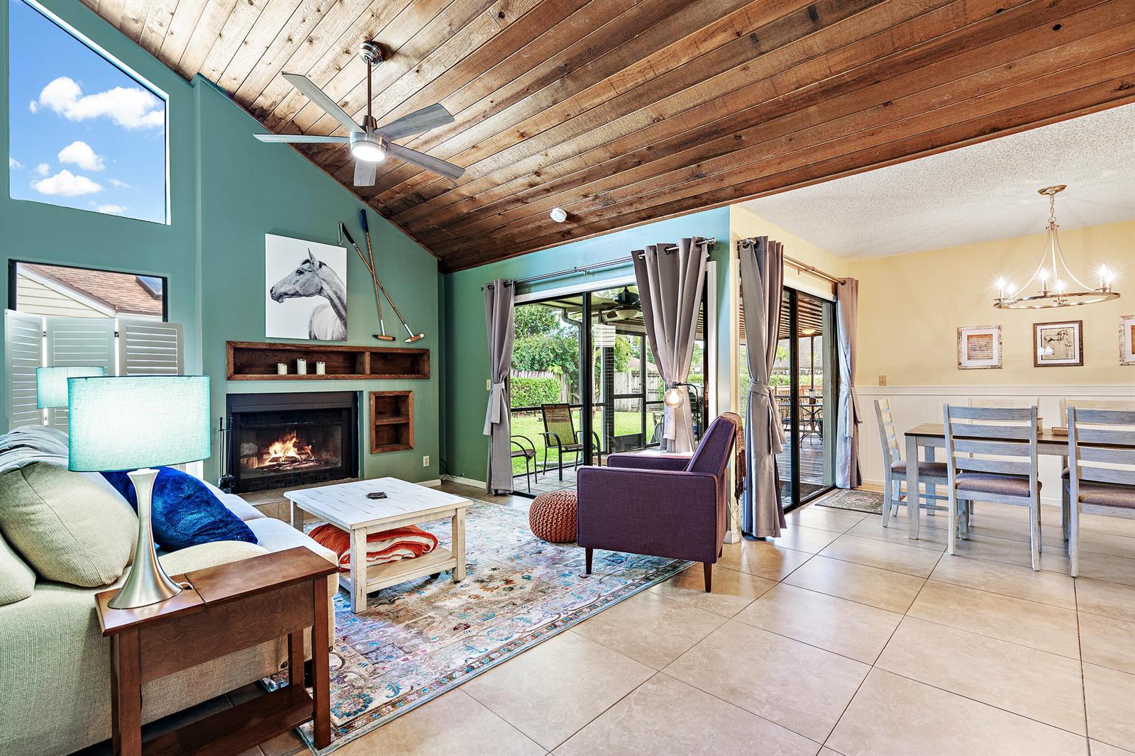 A living room with a vaulted wood ceiling, fireplace, and dining area on tile floors — 500 Oak Shadow Way, Wellington FL 33414, WELLINGTON, FL