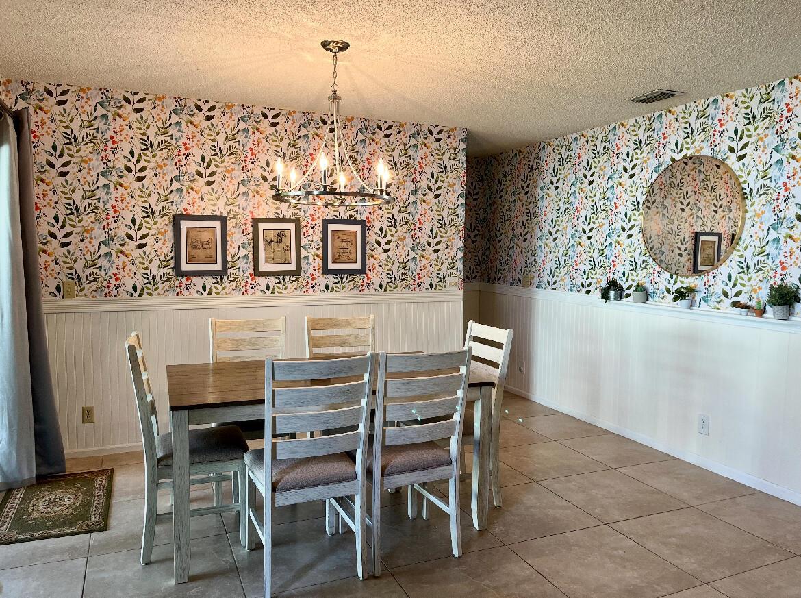 A dining room features floral wallpaper above white wainscoting, a wooden table, and a chandelier — 500 Oak Shadow Way, Wellington FL 33414, WELLINGTON, FL