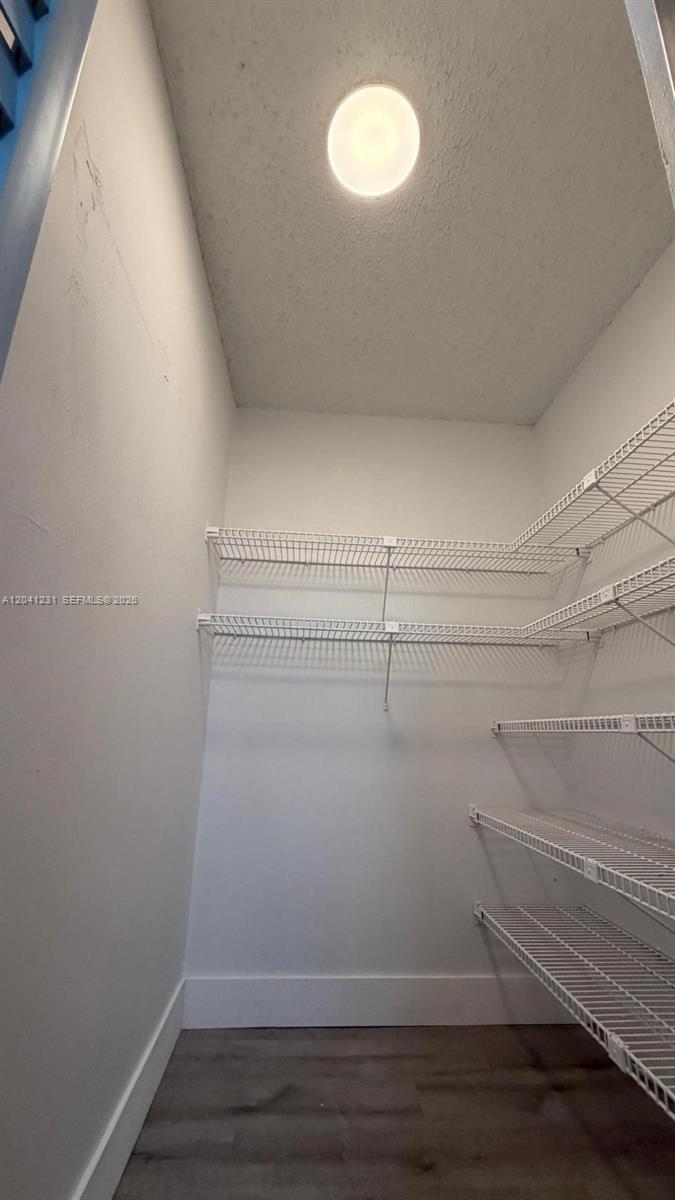 A walk-in closet features white wire shelving on two walls and wood-look flooring — 237 Lake Frances Dr # 237, West Palm Beach FL 33411, WEST PALM BEACH, FL