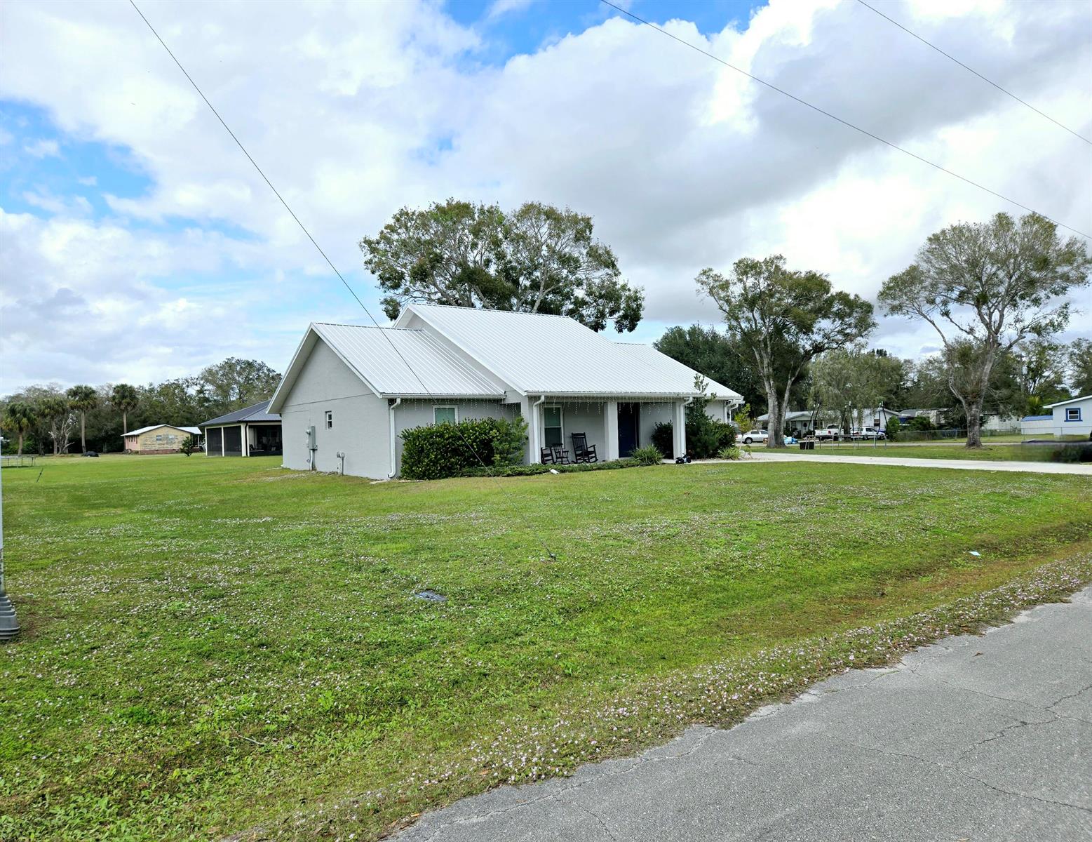 A light gray house with a metal roof sits on a large, grassy lot — 603 NW 11th Avenue, Okeechobee FL 34972, OKEECHOBEE, FL