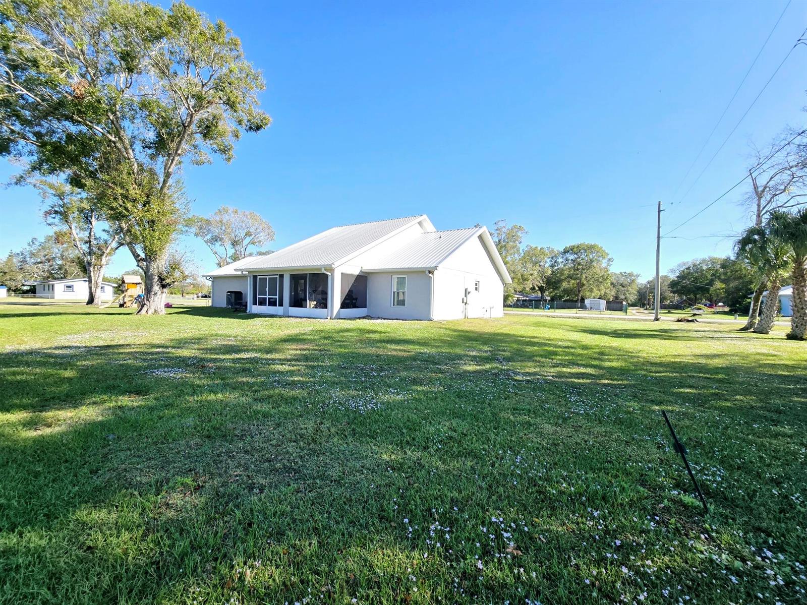 A white house with a metal roof and a screened-in porch sits on a grassy lot — 603 NW 11th Avenue, Okeechobee FL 34972, OKEECHOBEE, FL
