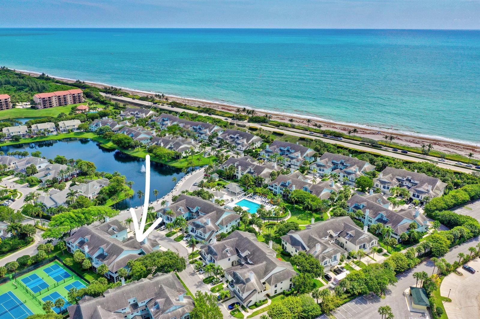 An aerial view of a coastal residential community featuring a pool, tennis courts, and lake — 1701 Mizzenmast Way, Jupiter FL 33477, JUPITER, FL