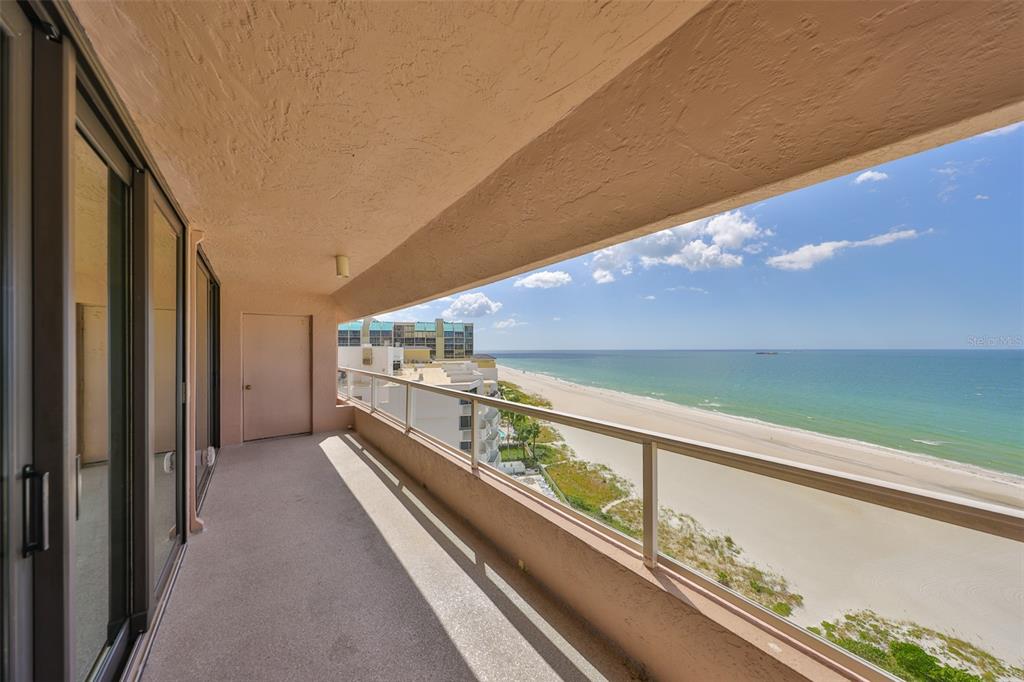 A covered balcony with a glass railing overlooks a sandy beach and the ocean — 1340 GULF BOULEVARD UNIT 11C, CLEARWATER BEACH, FL