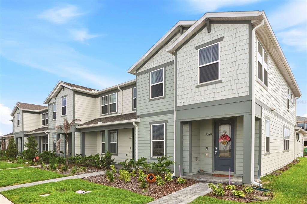 A two-story townhouse with light-colored siding, a covered entryway, and a small front yard — 10148 HADLEY STREET, ORLANDO, FL