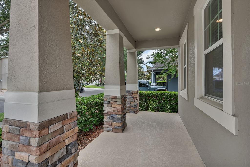 A covered front porch features stone-based columns, a concrete floor, and a recessed light — 12826 WOODMERE CLOSE DR, WINDERMERE, FL