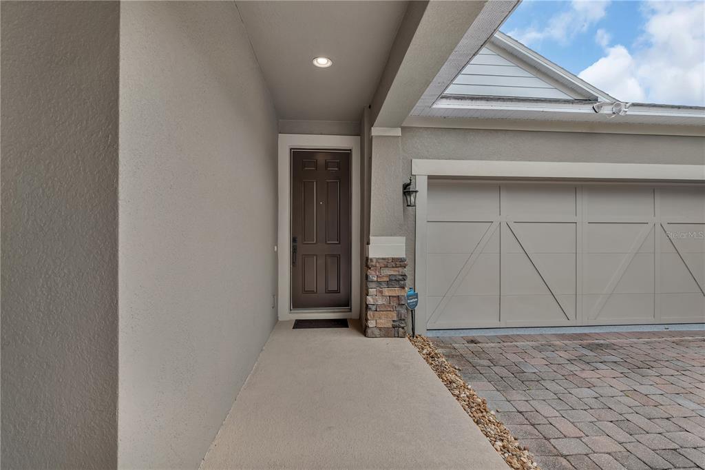 A covered entryway features a brown front door, stone accents, and a beige garage door — 12826 WOODMERE CLOSE DR, WINDERMERE, FL