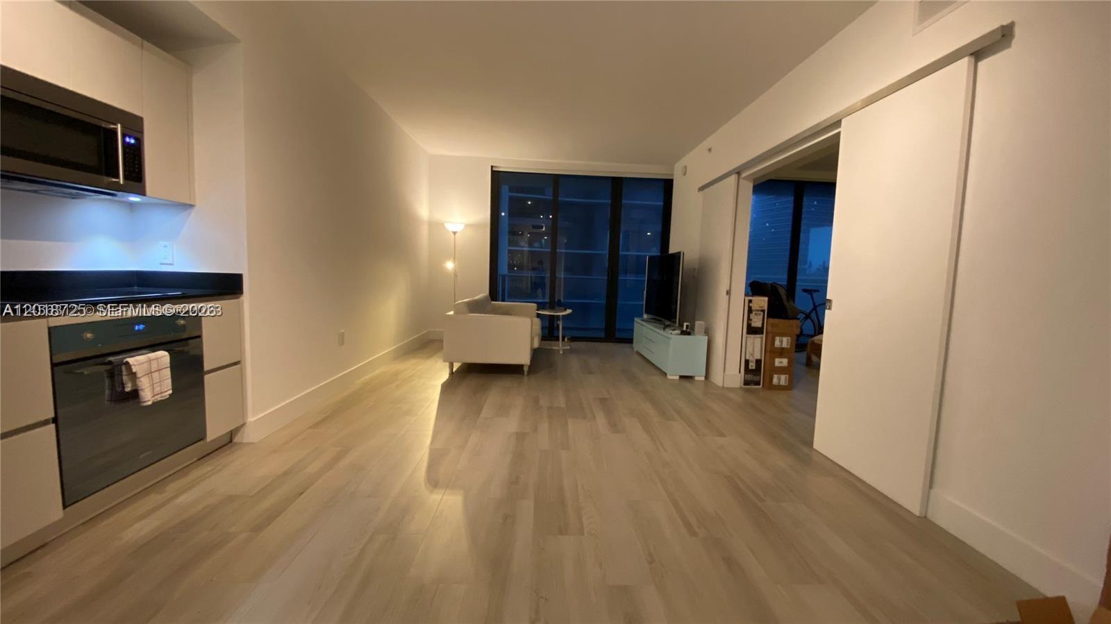 A modern apartment features an open-concept kitchen, living area, and sliding doors to a bedroom — 1010 Brickell Ave # 2208, Miami FL 33131, MIAMI, FL
