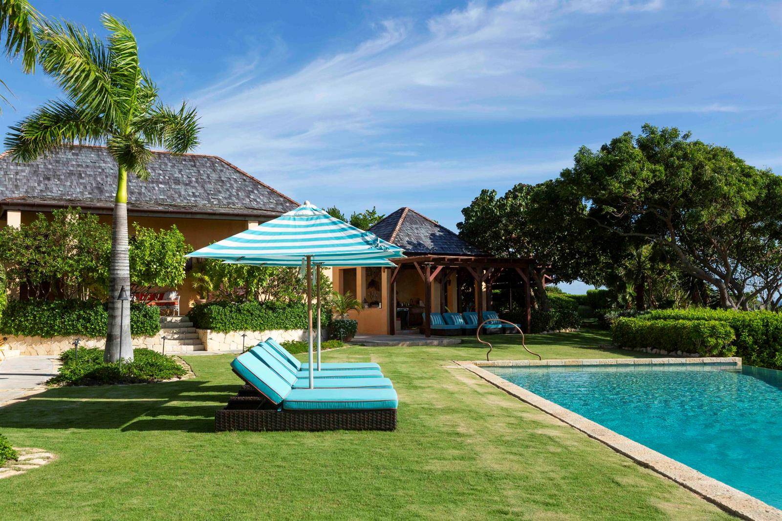 A swimming pool sits beside a lawn with lounge chairs and a striped umbrella — 0 Pelican Ridge, FL
