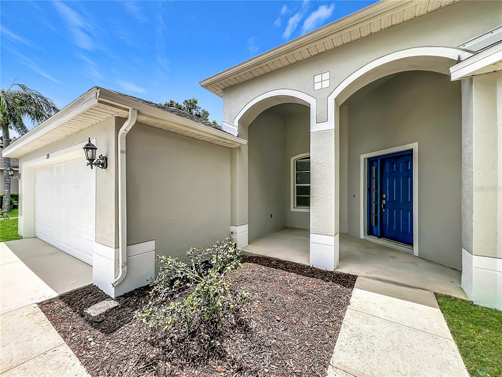 The exterior of a house features a blue front door, arched entryway, and garage — 235 MAGNOLIA PARK TRAIL, SANFORD, FL