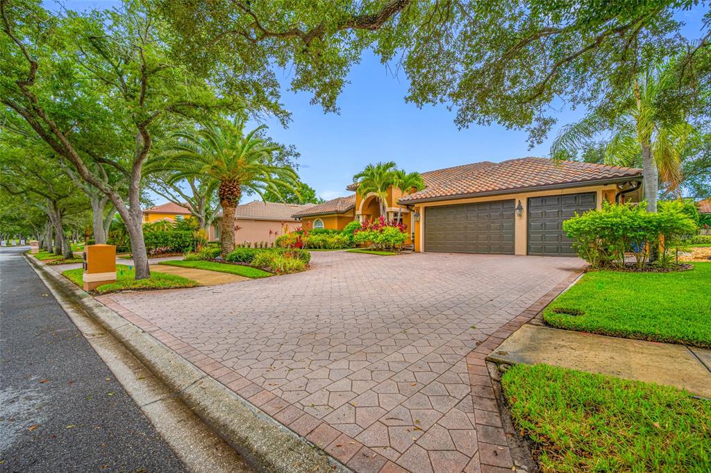 A single-story house with a paved driveway, two-car garage, and mature trees in the yard — 7888 BAYOU CLUB BOULEVARD, SEMINOLE, FL