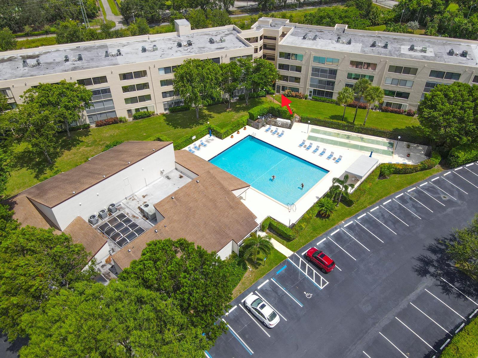 An aerial view shows a multi-story apartment building with a swimming pool and parking lot — 3154 Via Poinciana # 116, FL 33467, FL