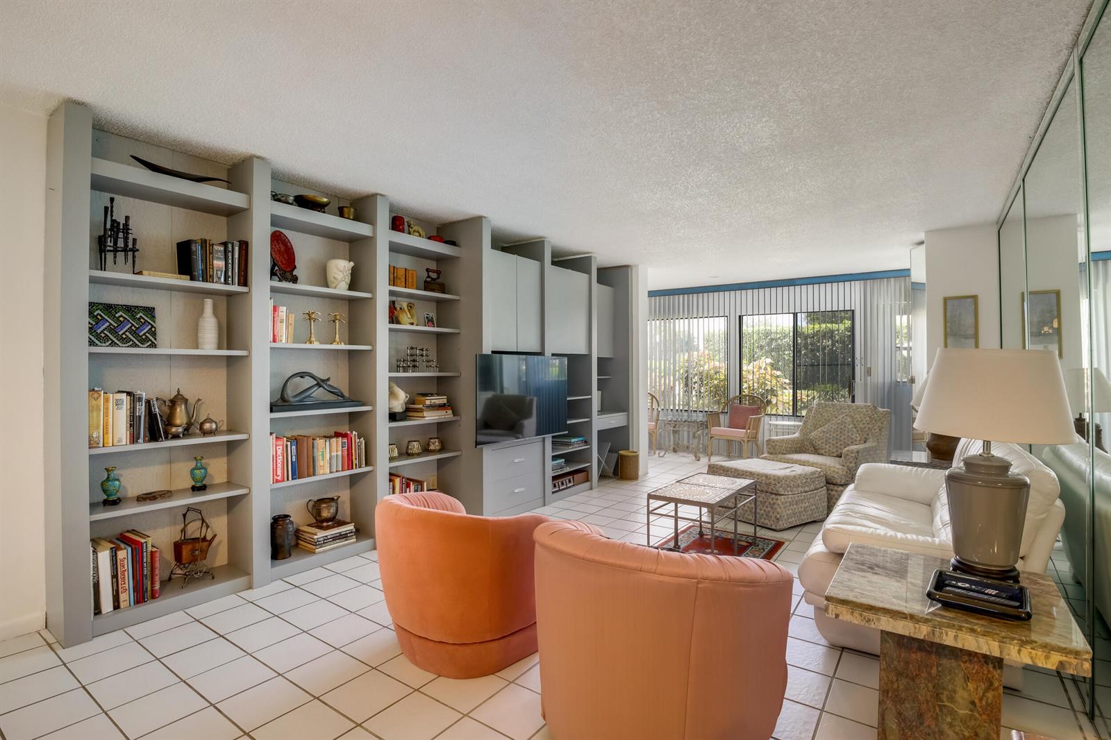 A living room features built-in gray shelving, two peach armchairs, a white sofa, and tile flooring — 3154 Via Poinciana # 116, FL 33467, FL