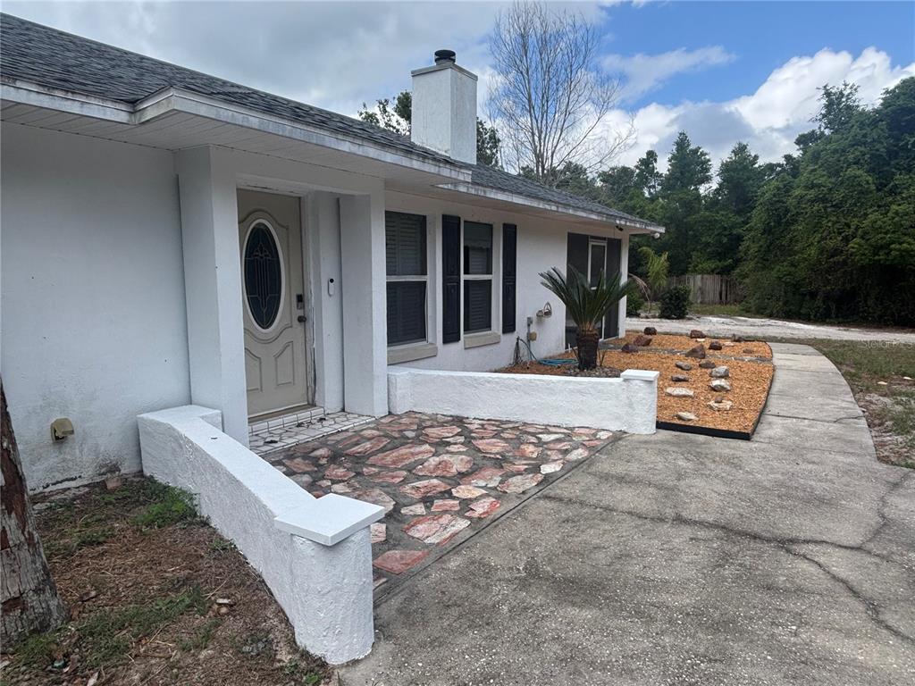 The exterior of a white house features a stone-paved entryway and a small rock garden — 510 S CEDAR AVENUE, ORANGE CITY, FL