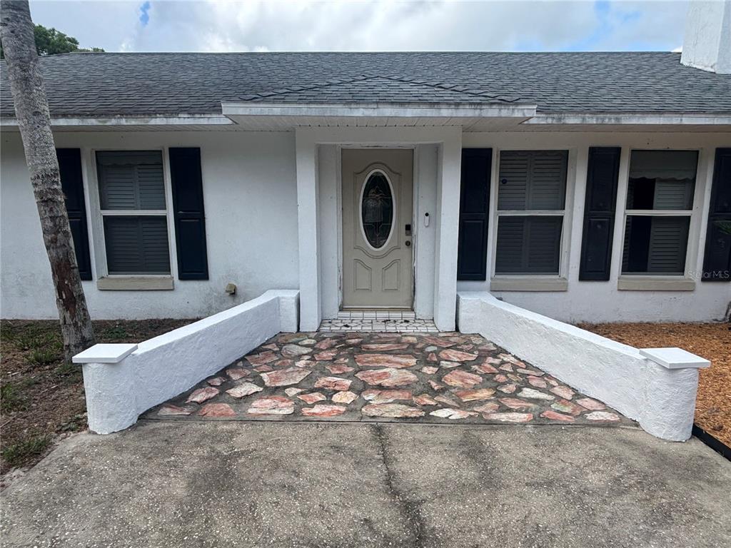 The exterior of a white house features a stone-paved walkway leading to the front door — 510 S CEDAR AVENUE, ORANGE CITY, FL