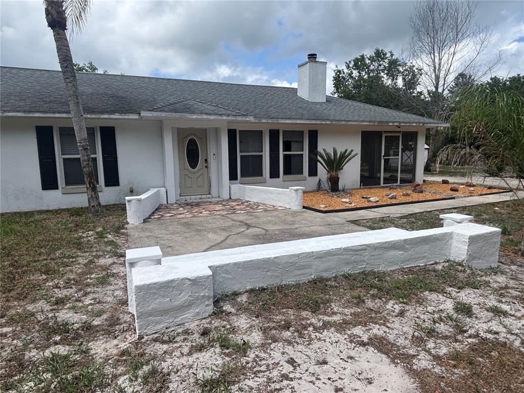 A single-story house with a white exterior, a front patio, and a low masonry wall — 510 S CEDAR AVENUE, ORANGE CITY, FL
