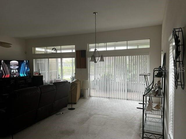 A living room features a dark leather sofa, a television, and large sliding glass doors — 8407 OAK JAY LANE, ENGLEWOOD, FL