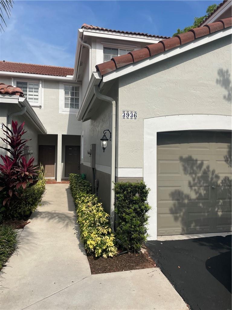 A two-story townhouse exterior features a beige stucco facade, a garage, and a walkway — 3936 San Simeon Lane # 3936, Weston FL 33331, WESTON, FL