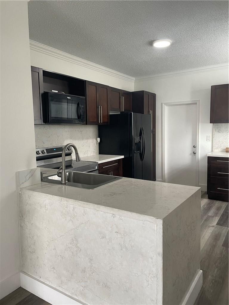 A kitchen with dark wood cabinets, stainless steel appliances, and a white stone countertop island — 3936 San Simeon Lane # 3936, Weston FL 33331, WESTON, FL