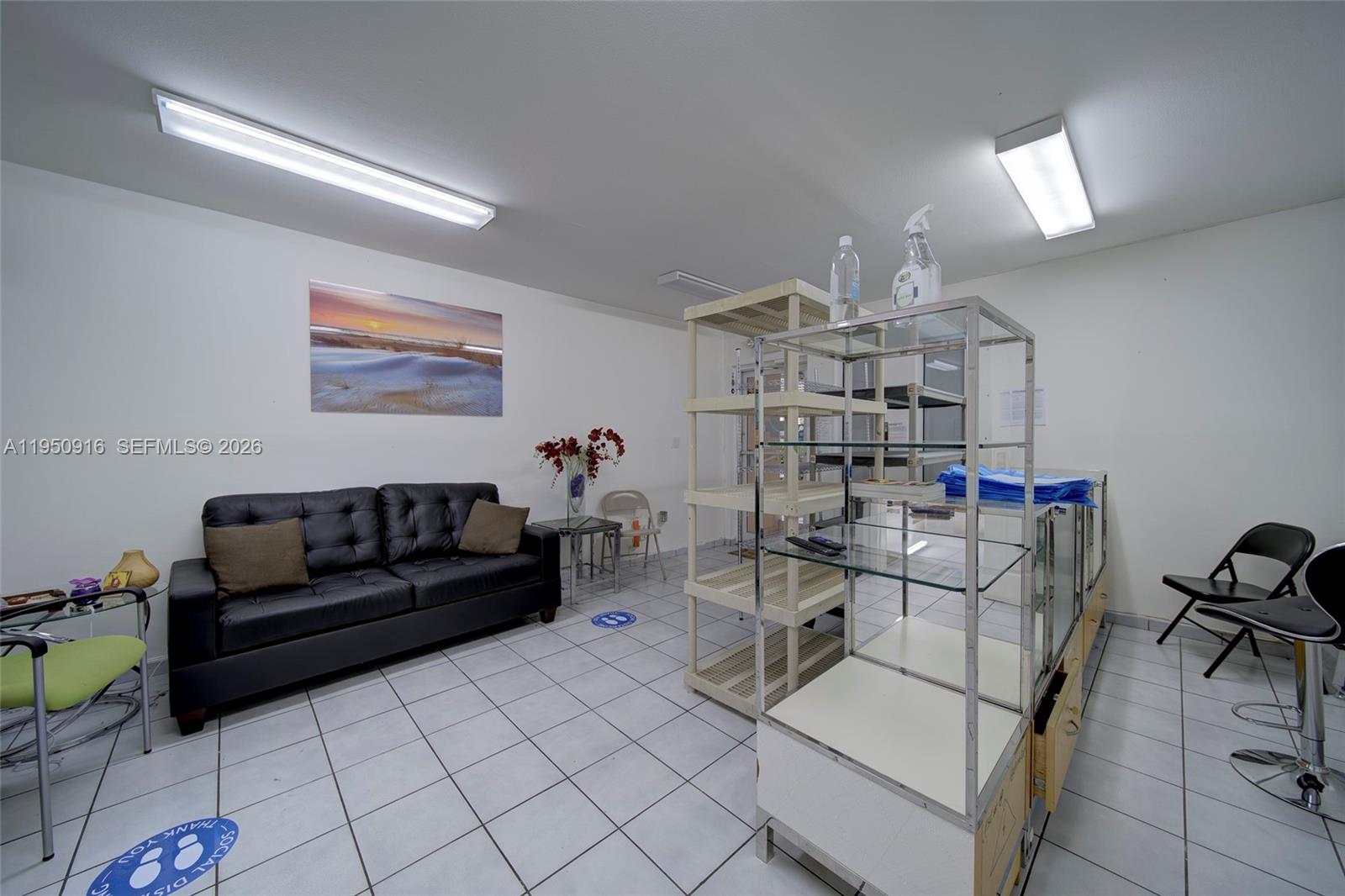 A waiting area features a black leather sofa, tile flooring, and metal shelving units — 330 W 9th St, Hialeah FL 33010, HIALEAH, FL