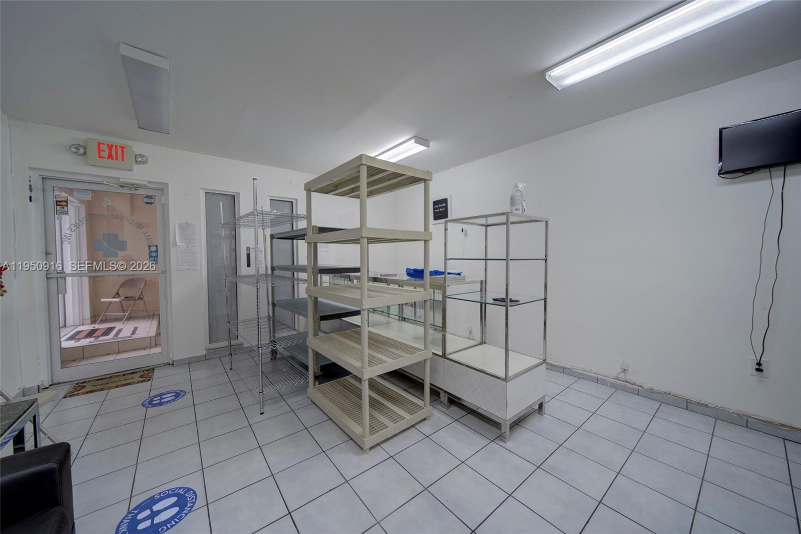 A commercial room with white walls, tiled floors, metal shelving units, and a glass door — 330 W 9th St, Hialeah FL 33010, HIALEAH, FL