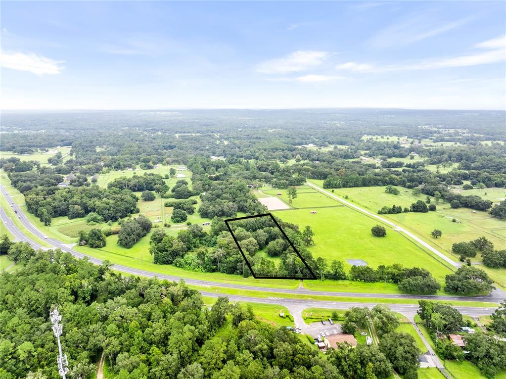 An aerial view shows a wooded plot of land outlined in black near a highway — 12255 N US HIGHWAY 27, OCALA, FL