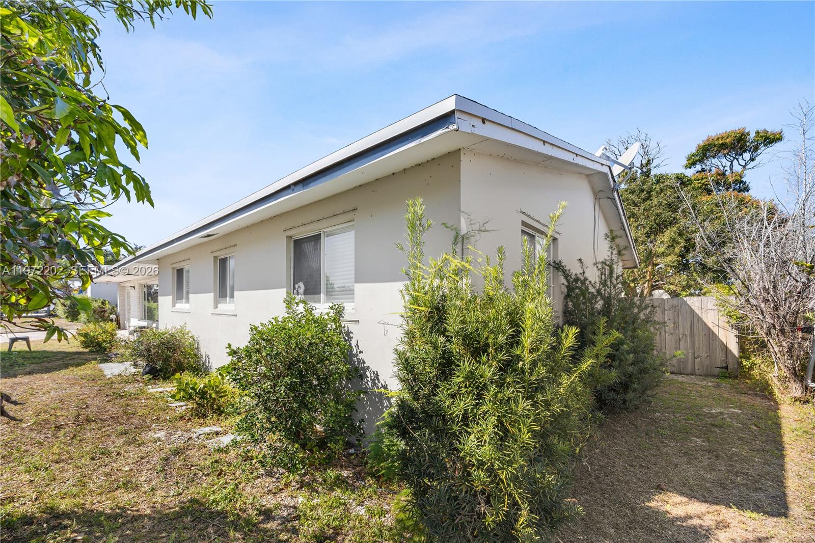 A side view of a single-story house with light-colored stucco walls and a flat roof — 227 SW 13th Ave, Boynton Beach FL 33435, BOYNTON BEACH, FL
