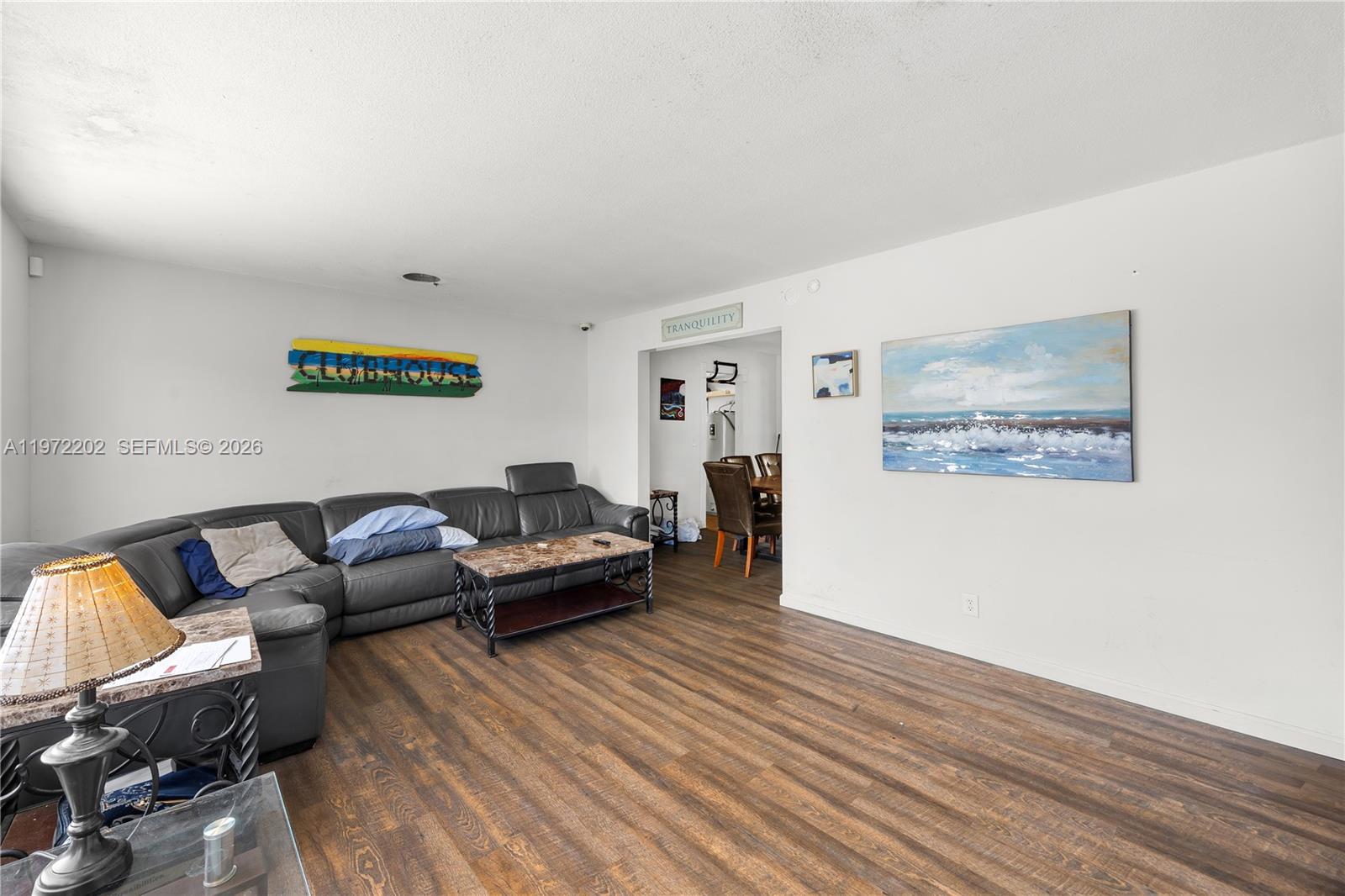 A living room features a dark leather sectional, wood-look flooring, and a large ocean painting — 227 SW 13th Ave, Boynton Beach FL 33435, BOYNTON BEACH, FL