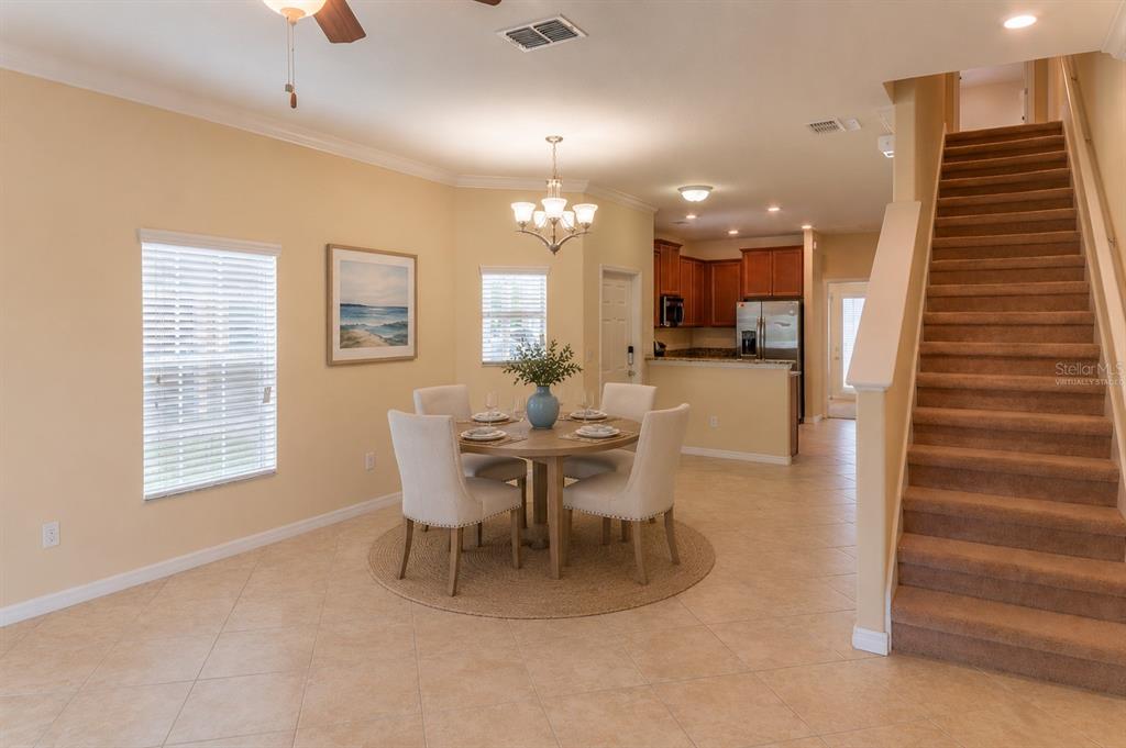 A dining area with a round table and chairs sits beside a staircase and kitchen — 31235 CLARIDGE PLACE, WESLEY CHAPEL, FL