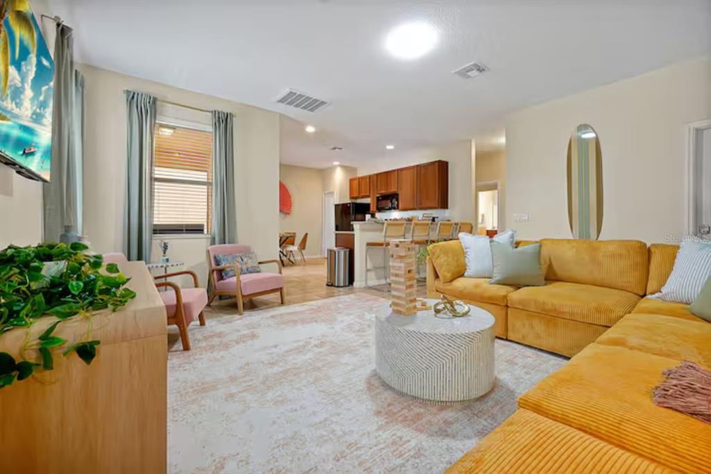 A living room features a yellow sectional sofa, a round coffee table, and an open kitchen — 2650 SANTOSH COVE, KISSIMMEE, FL