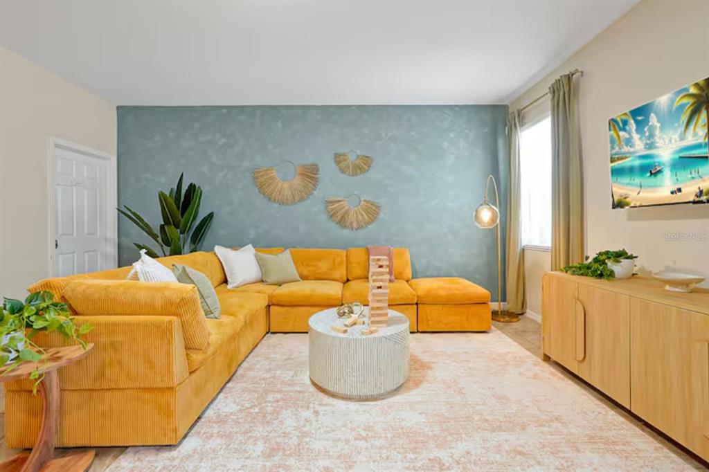 A living room features a yellow sectional sofa, a textured blue wall, and a coffee table — 2650 SANTOSH COVE, KISSIMMEE, FL