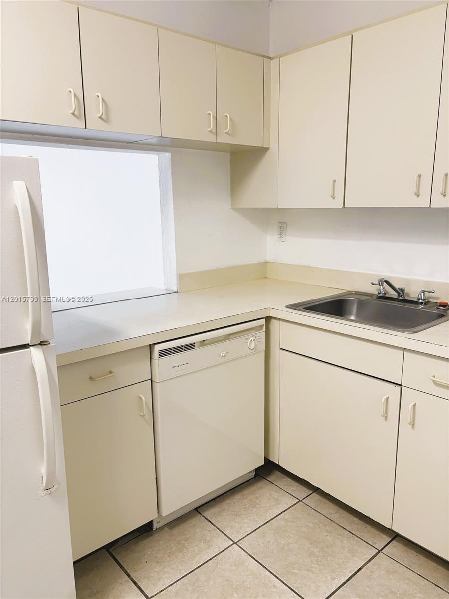 A kitchen features white cabinetry, a dishwasher, a stainless steel sink, and tiled flooring — 10900 SW 104th St # 315, Miami FL 33176, MIAMI, FL