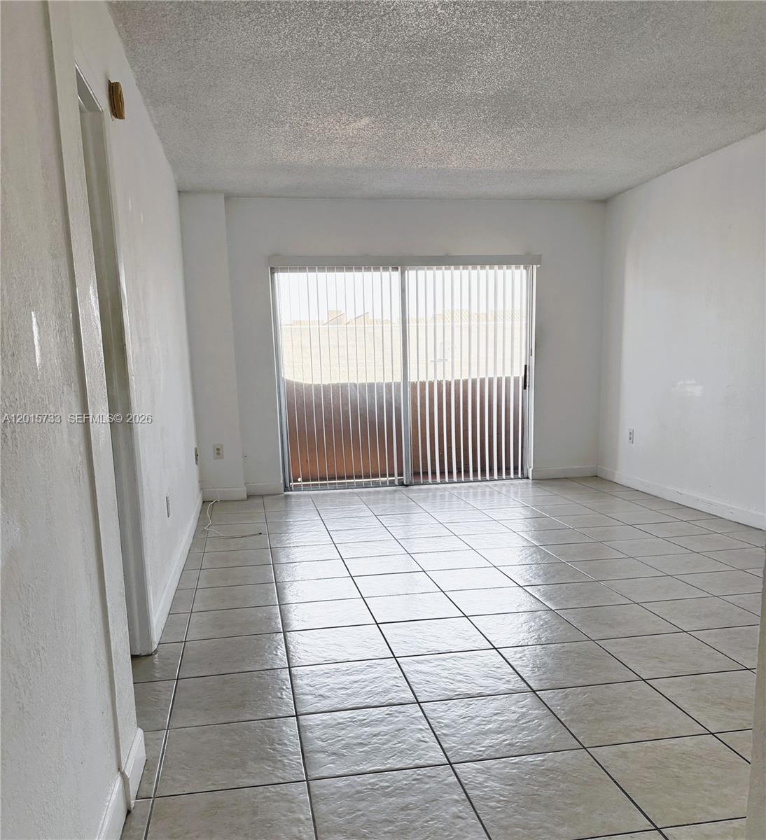 An empty room features white walls, light-colored tile flooring, and a sliding glass door — 10900 SW 104th St # 315, Miami FL 33176, MIAMI, FL