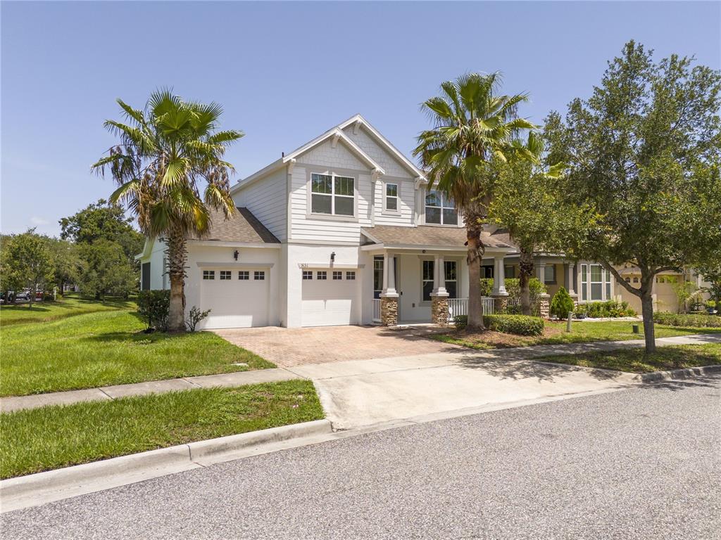 A two-story house with a white exterior, a front porch, and palm trees in the yard — 5131 MILLENNIA GREEN DRIVE, ORLANDO, FL