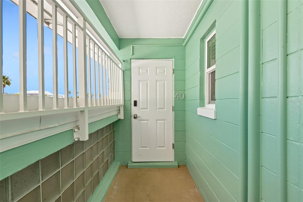 A mint green exterior entryway features a white door labeled 40 and a metal railing — 11730 GULF BOULEVARD UNIT 40, ST PETERSBURG, FL