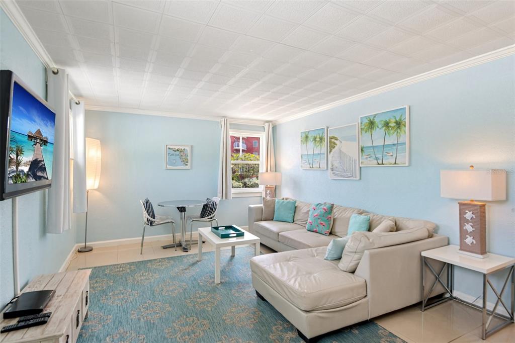 A living room features a sectional sofa, a small dining table, and light blue walls — 11730 GULF BOULEVARD UNIT 40, ST PETERSBURG, FL