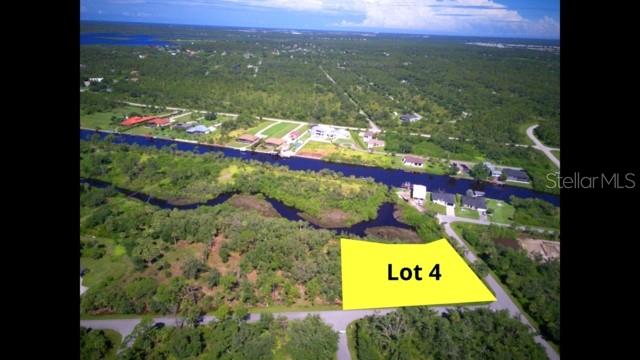 An aerial view shows a highlighted vacant lot near a canal and residential homes — 1157 CASPER STREET, PORT CHARLOTTE, FL
