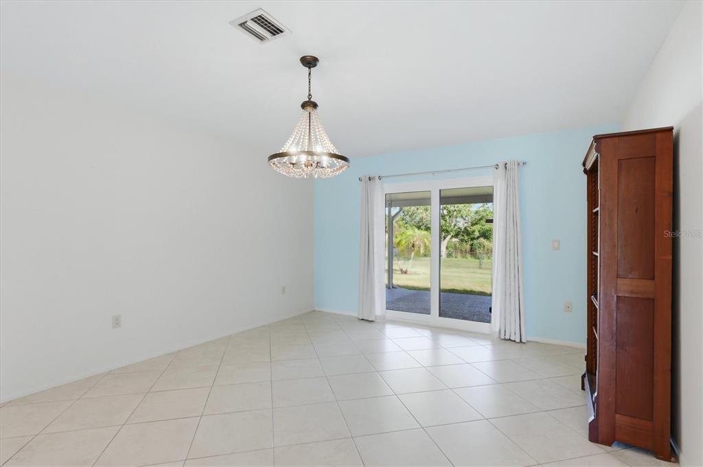 A dining room features tile flooring, a crystal chandelier, and sliding glass doors to a yard — 255 RIGEL ROAD, VENICE, FL