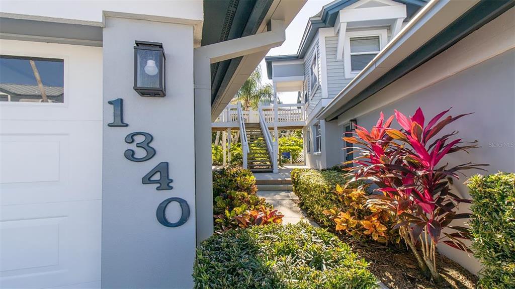 The exterior of a house features a vertical address number, a light fixture, and landscaping — 1340 SIESTA BAYSIDE DRIVE UNIT 1340-C, SARASOTA, FL
