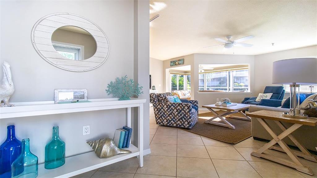 A bright living room features tiled floors, a patterned armchair, and a white console table — 1340 SIESTA BAYSIDE DRIVE UNIT 1340-C, SARASOTA, FL
